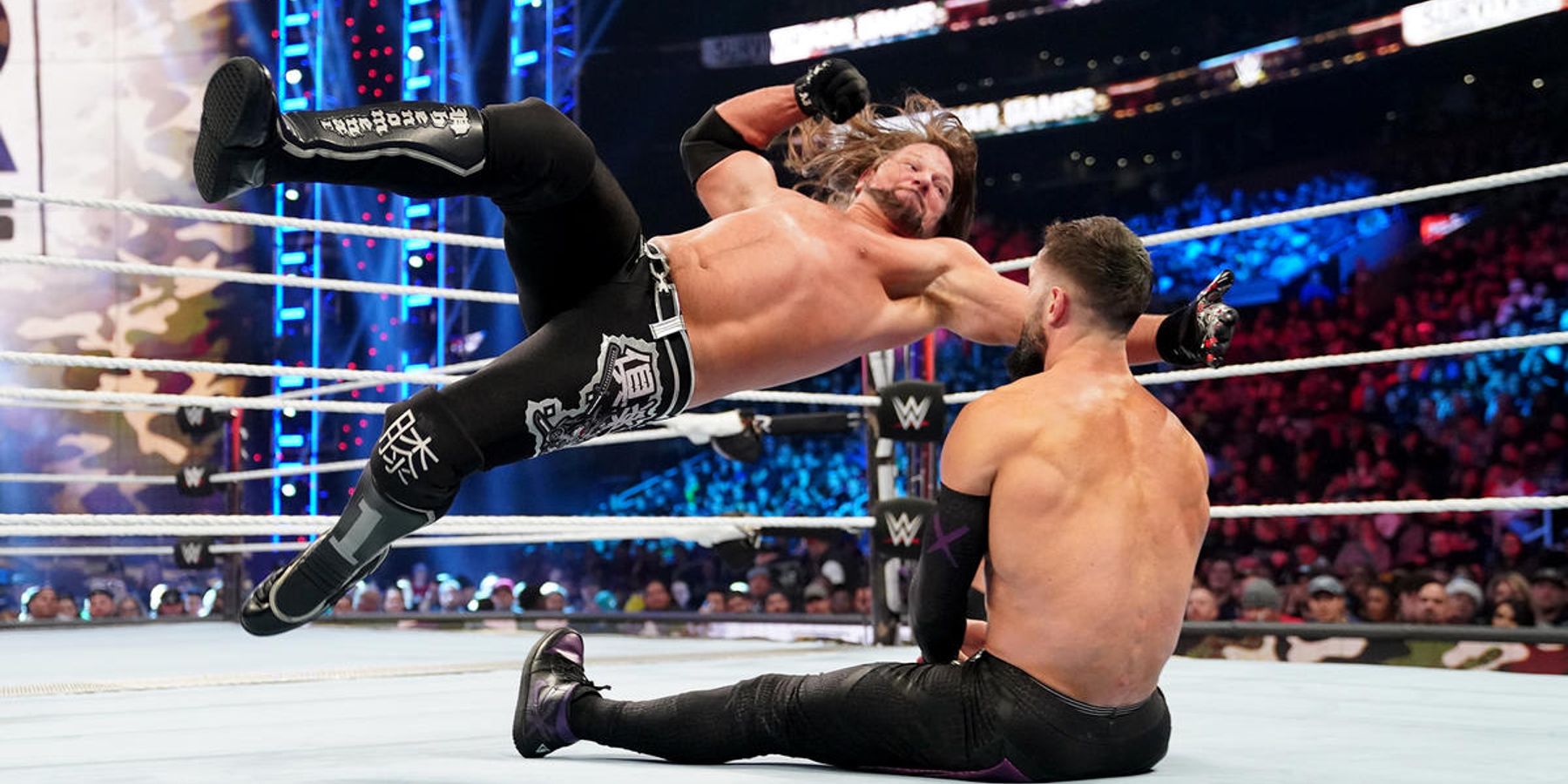 AJ Styles levert een vliegende onderarm aan een neergestorte Finn Balor in een WWE-wedstrijd in 2022.