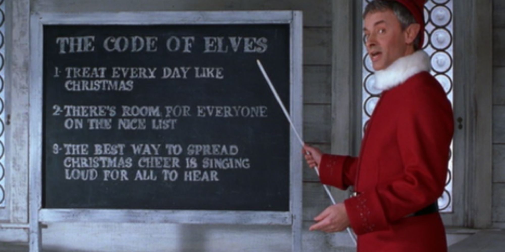 An elf pointing at the code of the elves on a blackboard in Elf
