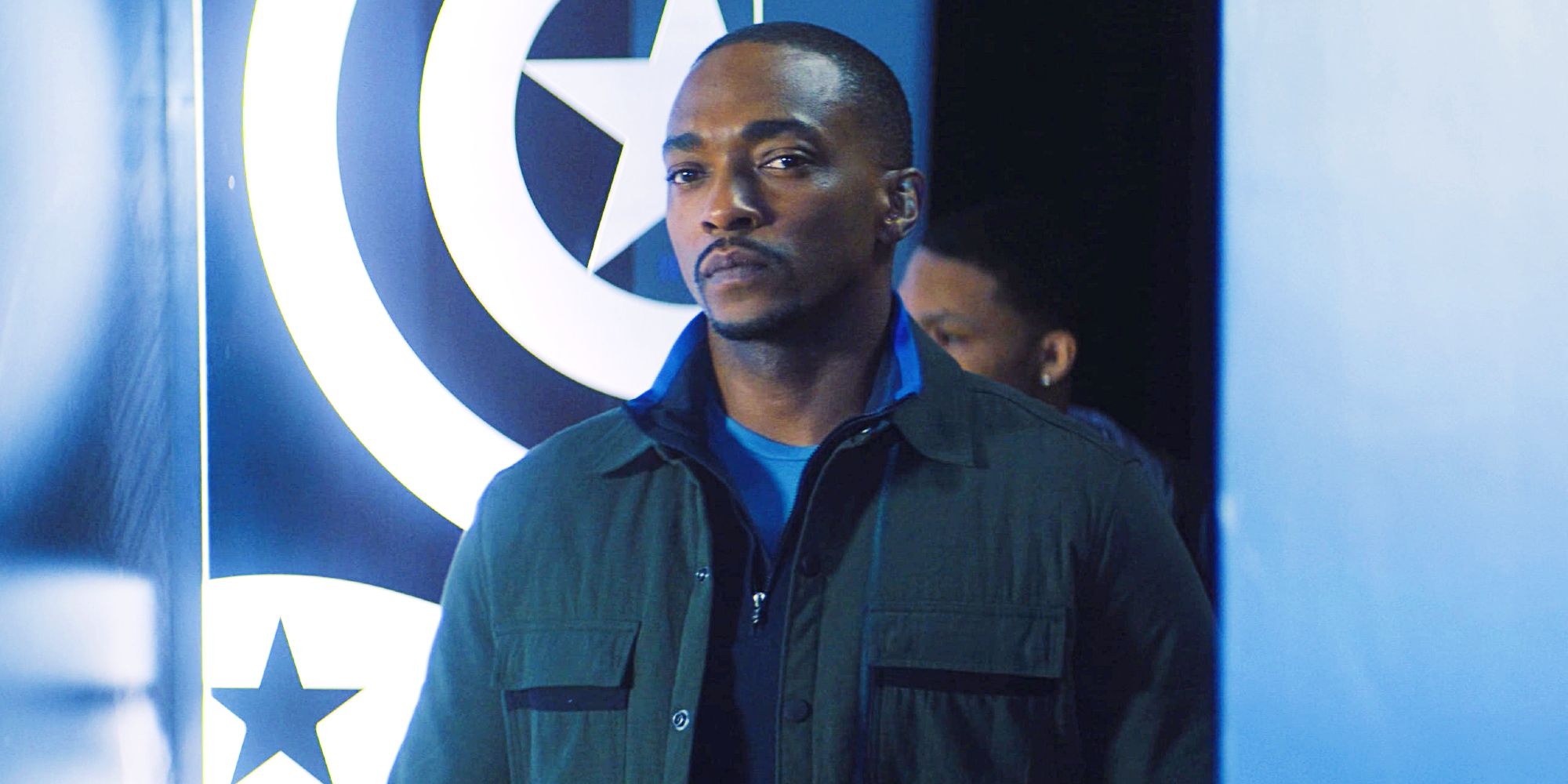 Anthony Mackie as Sam Wilson standing solemnly in Captain America exhibit in Falcon and the Winter Soldier