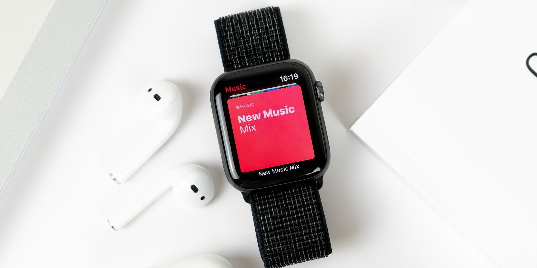 Apple Music playing on an Apple Watch, a pair of Airpods on the left