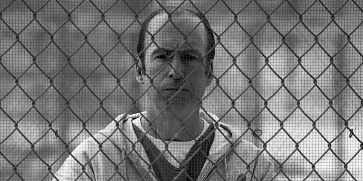 Bob Odenkirk as Saul Goodman standing behind jail fence in Better Call Saul series finale.