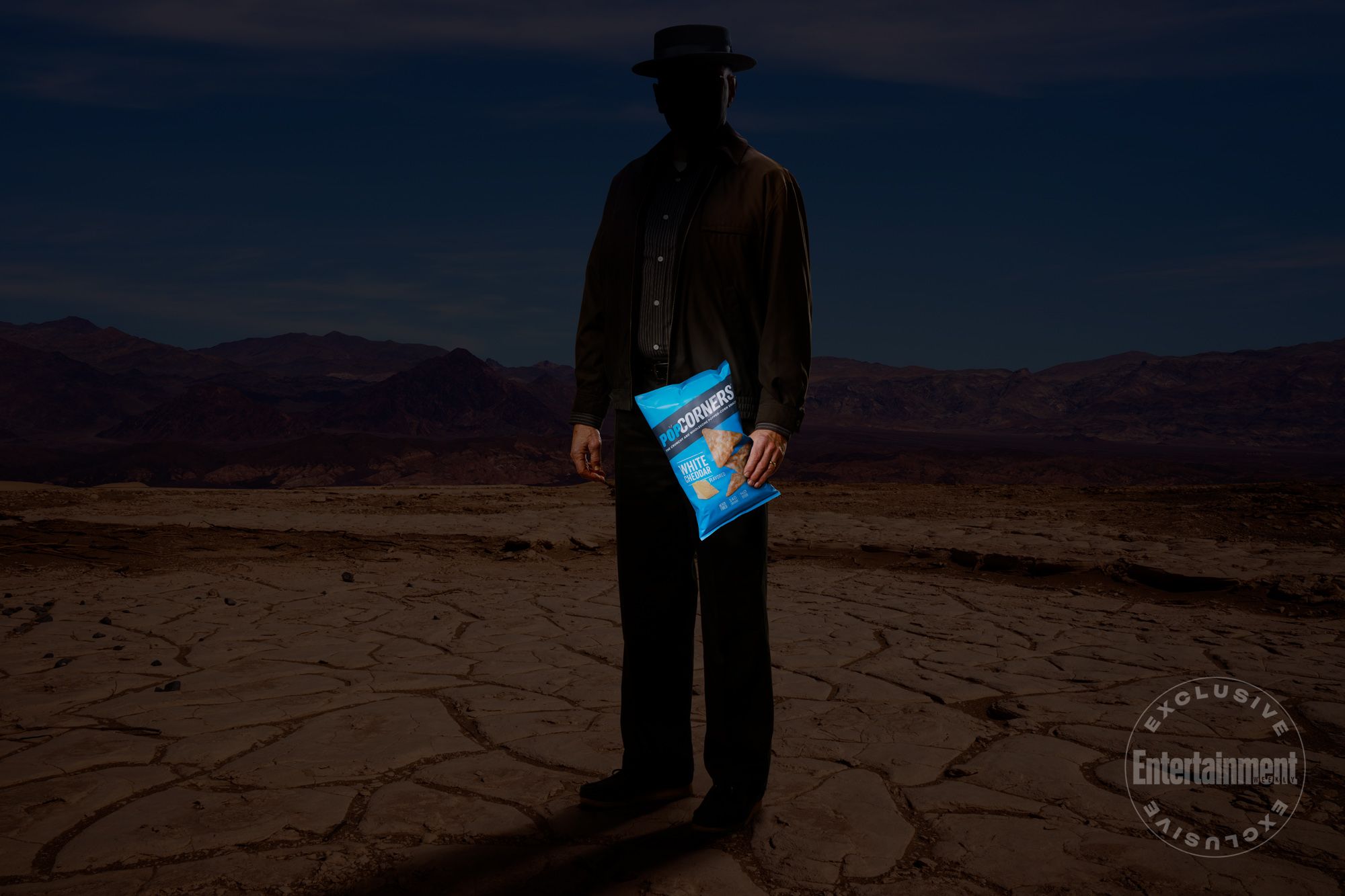 Uma misteriosa figura sombria que parece ser Walter White, de Breaking Bad, está no deserto segurando um saco de salgadinhos PopCorners na mão