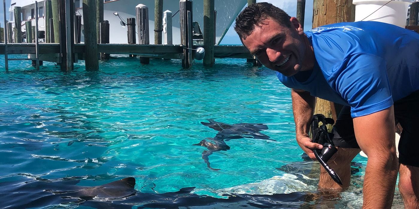 Captain Seth Jacobson from Below Deck Adventure smiling in front of animal in water