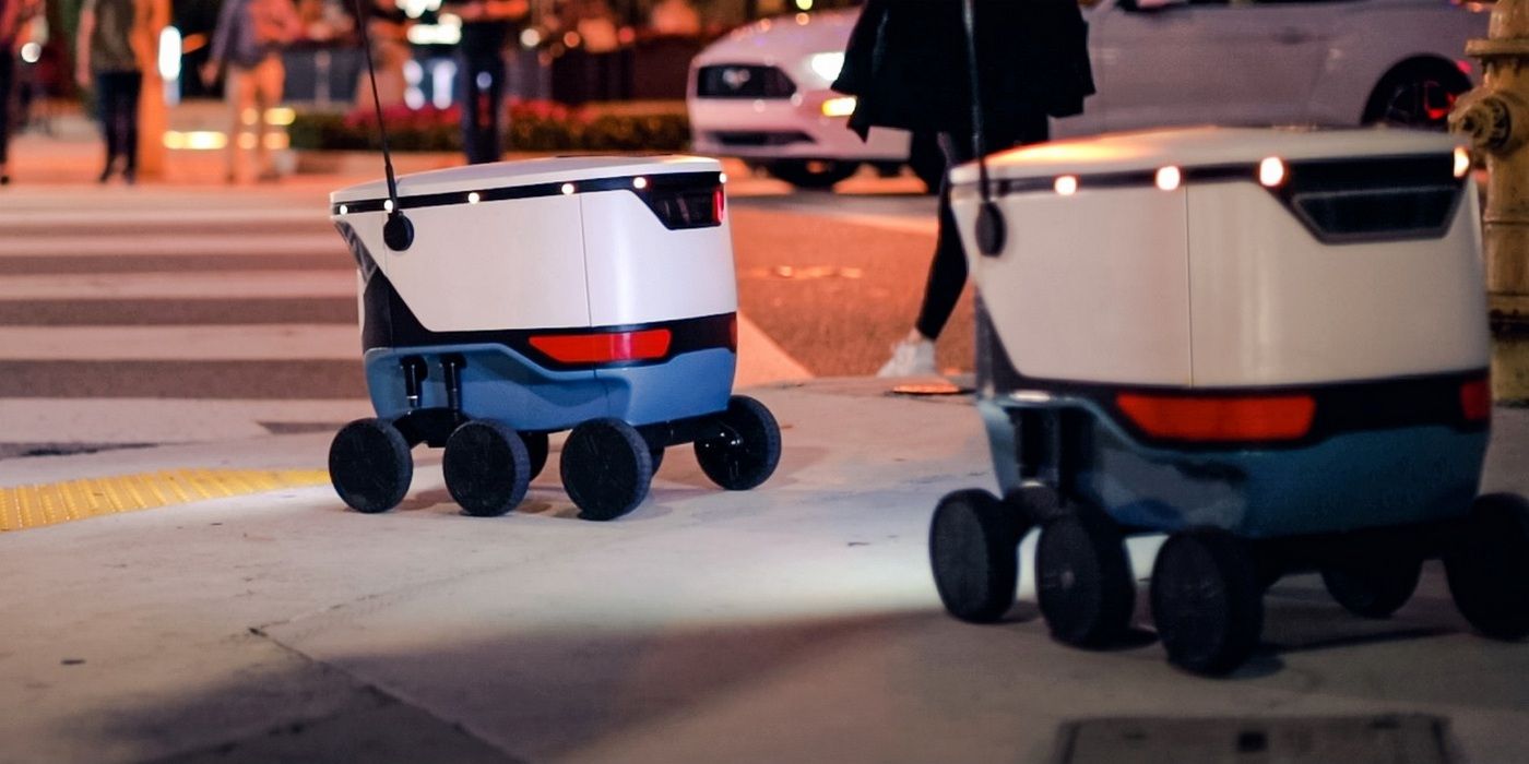Dois robôs entregadores Cartken são mostrados dirigindo em uma calçada