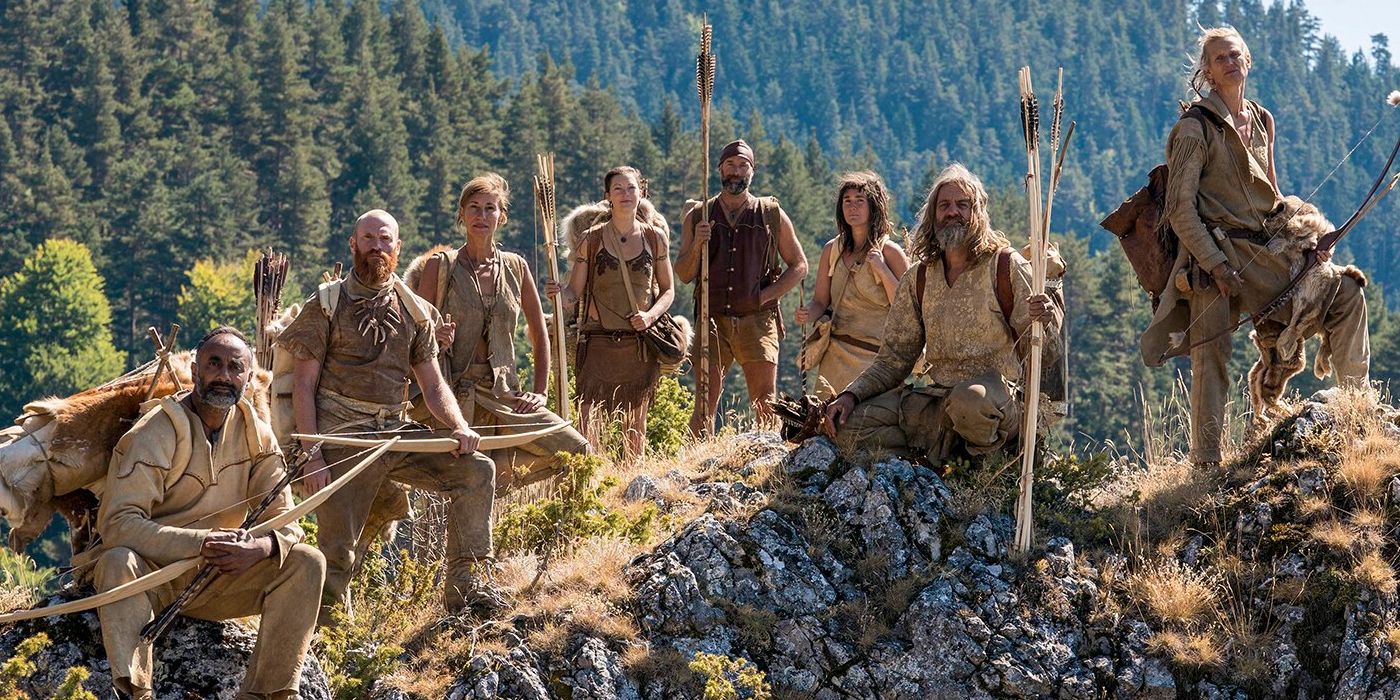 O elenco de Surviving the Stone Age posa junto em uma rocha com vista para a floresta