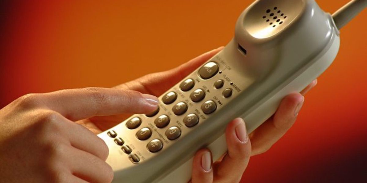 A hand dials an early cordless phone 