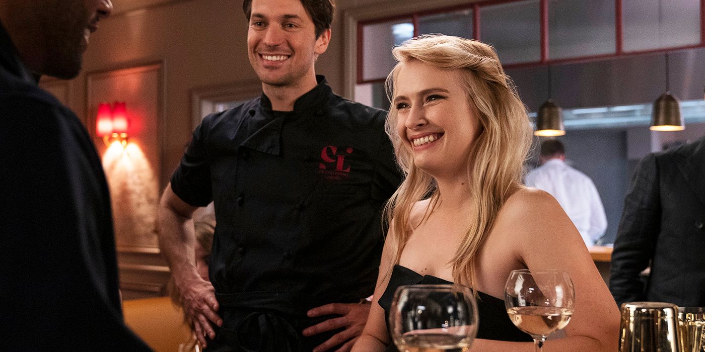 Camille smiling while standing in a restaurant in Emily in Paris.