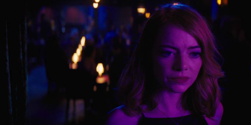 Emma Stone as Mia standing in a jazz club looking sad in La La Land