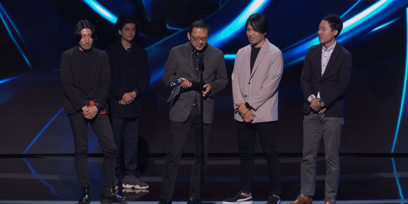 An image of the Elden Ring team's acceptance speech at the Game Awards, with the mysterious individual who interrupted the moment in the background 