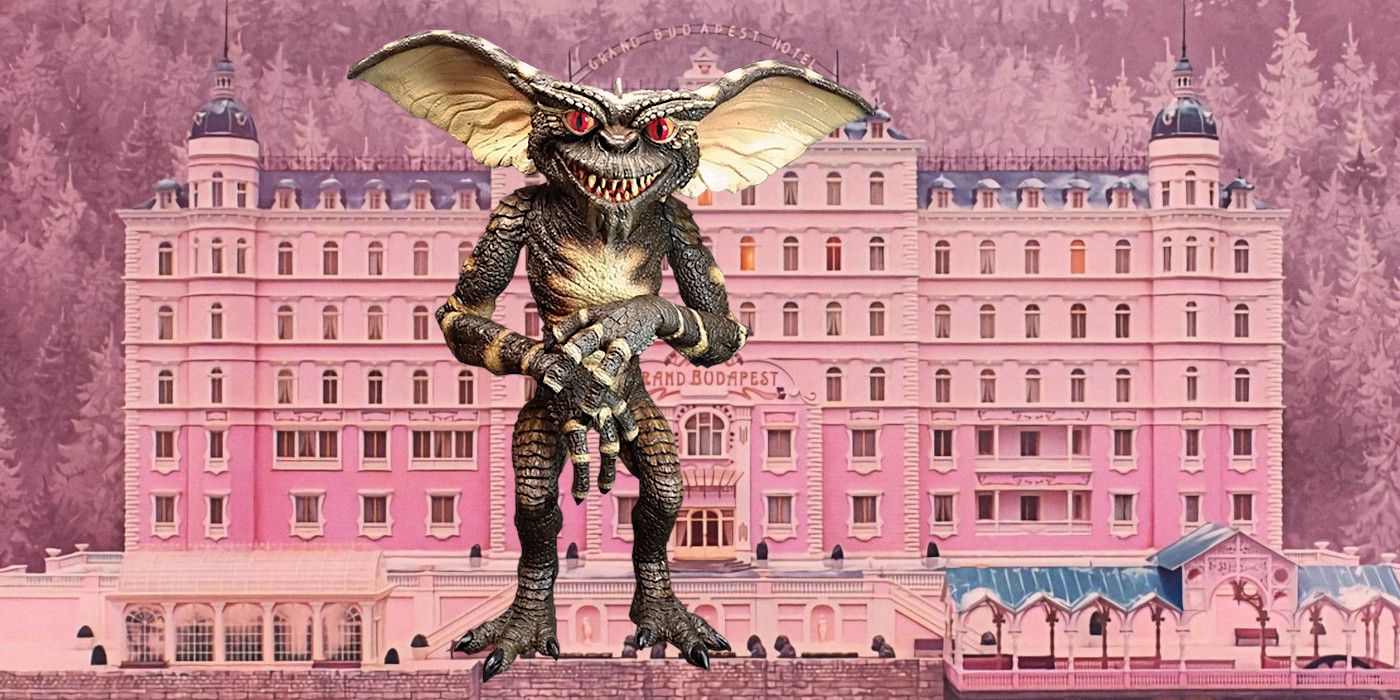 Slimy green Gremlin stands grinning in front of a giant picturesque pink stone building