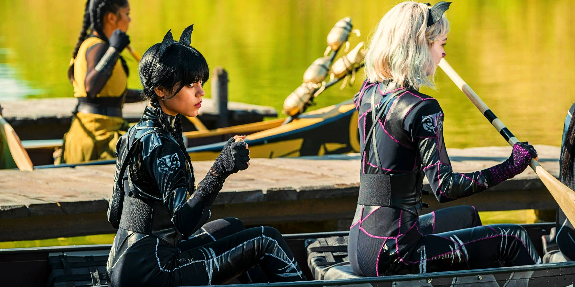 Jenna Ortega as Wednesday Addams and Emma Myers as Enid Sinclair wearing catsuits and rowing in Wednesday