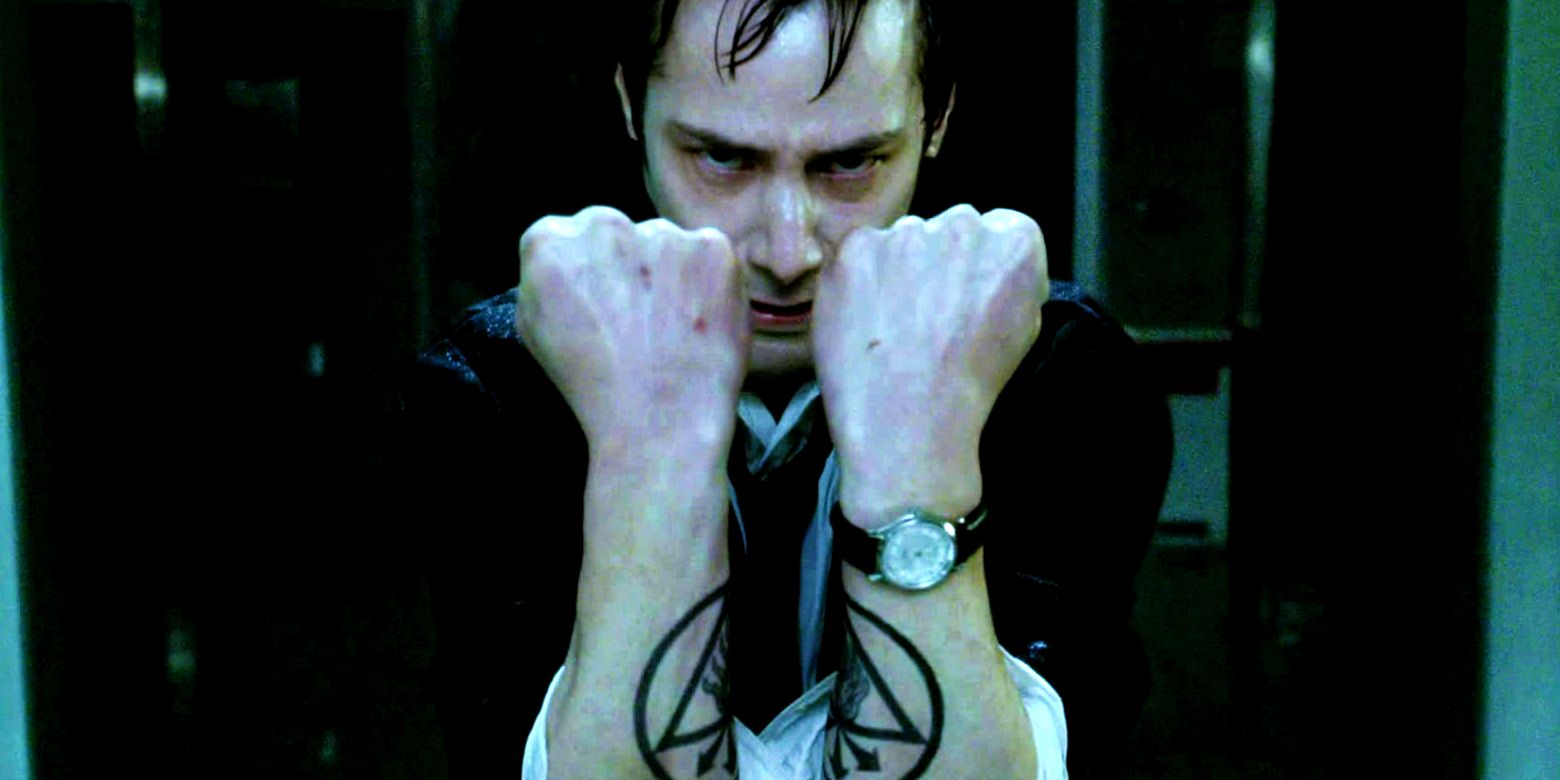 Keanu Reeves como John Constantine com os braços à sua frente em Constantine