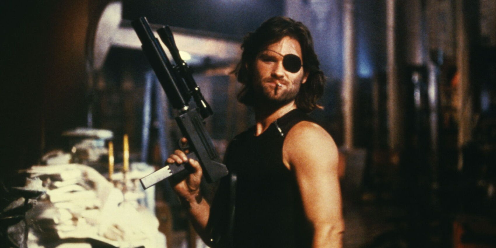 Kurt Russell as Snake Plisken holding up a gun and smoking in Escape From New York