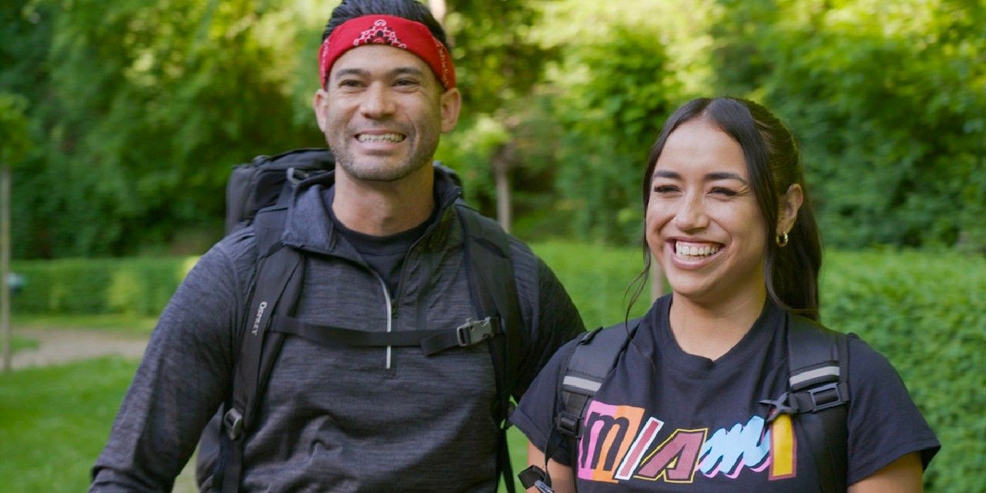 Luis e Michelle de The Amazing Race em camisas cinza sorrindo para a câmera.