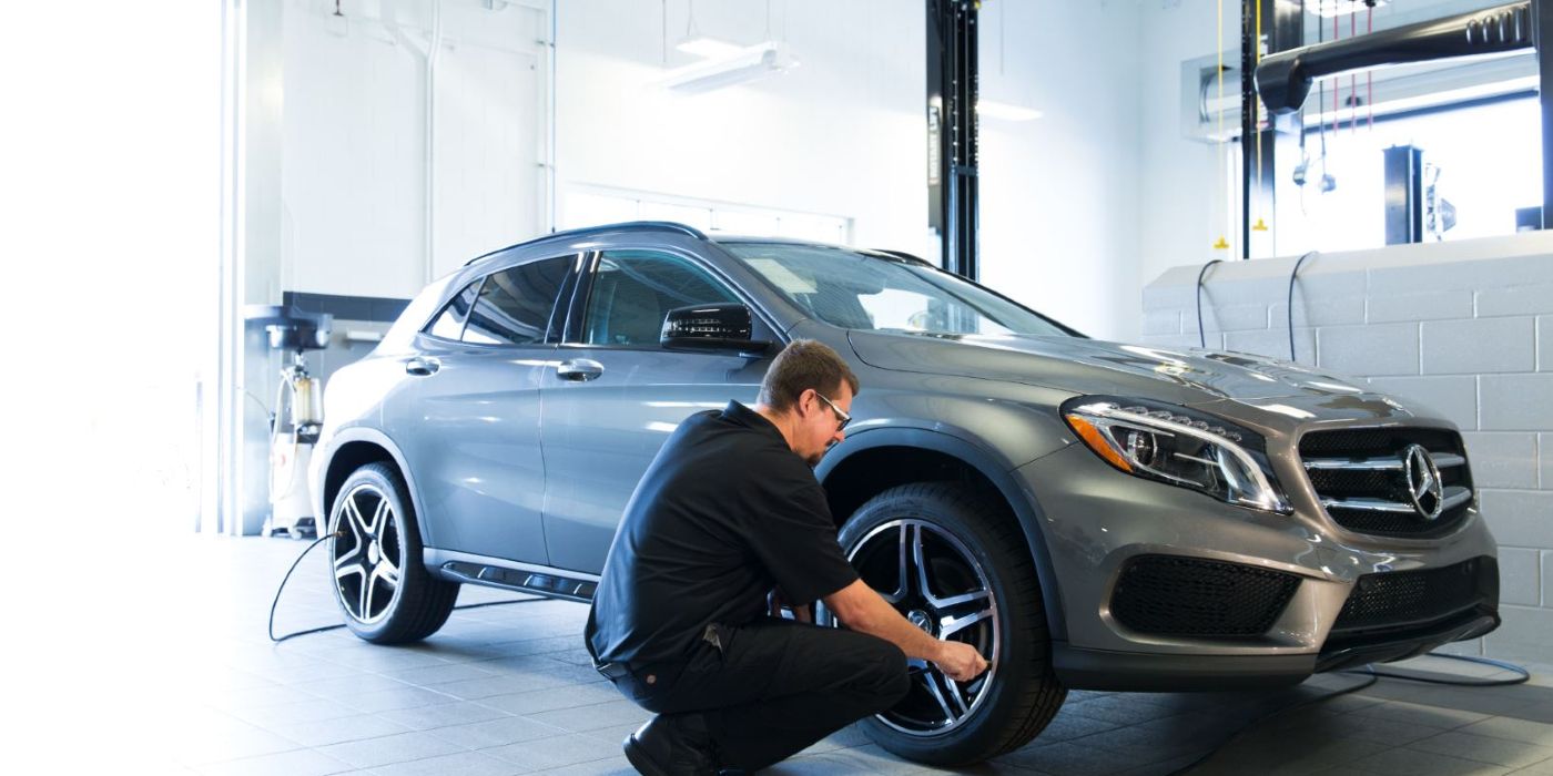 A Mercedes SUV  being worked on by a mechanic