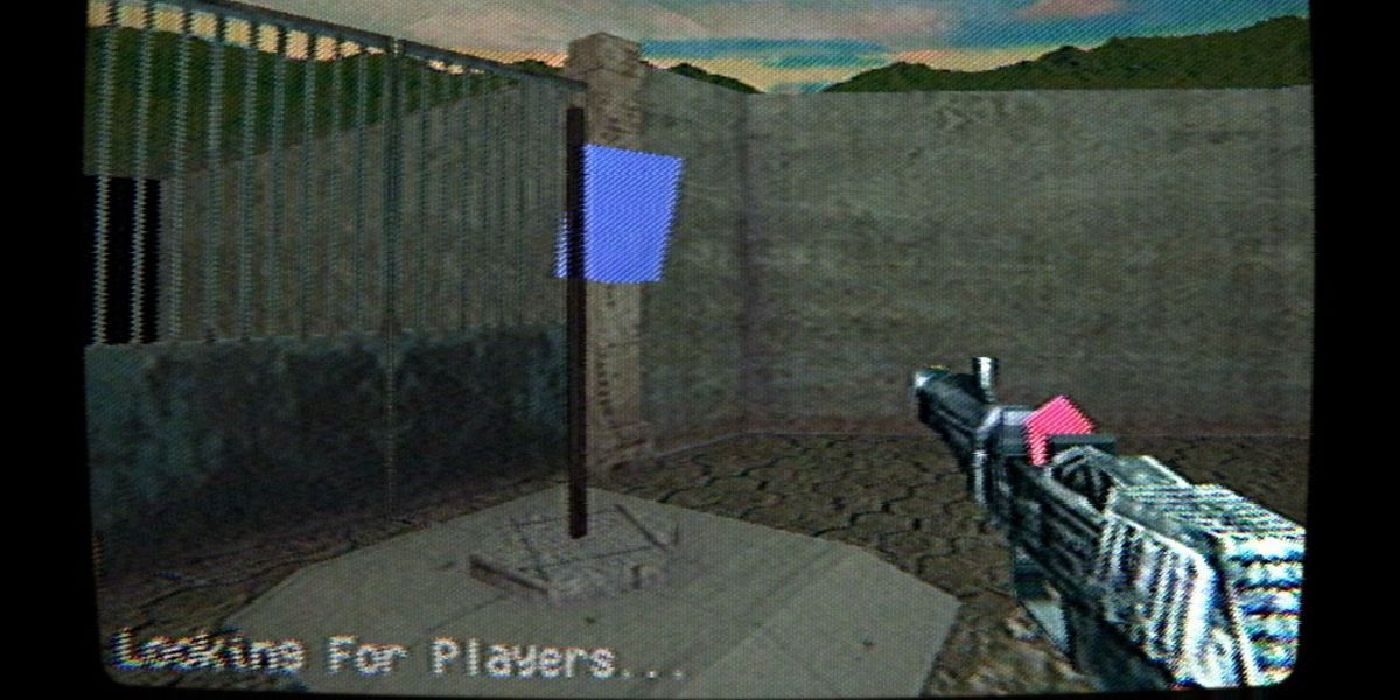 Um jogador com uma arma se aproxima de uma bandeira azul enquanto a tela afirma que está procurando jogadores