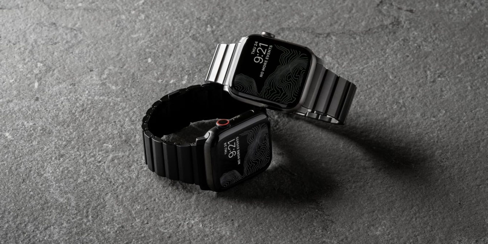 Nomad's black and silver titanium Apple Watch bands on two Apple Watch units.