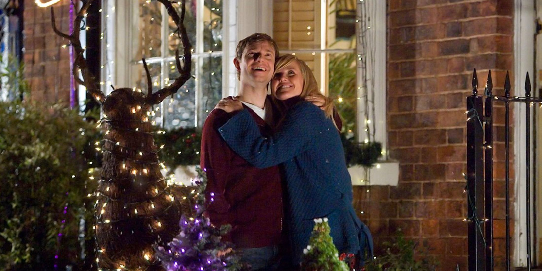 Paul and Jennifer hug surrounded by fairy lights in Nativity