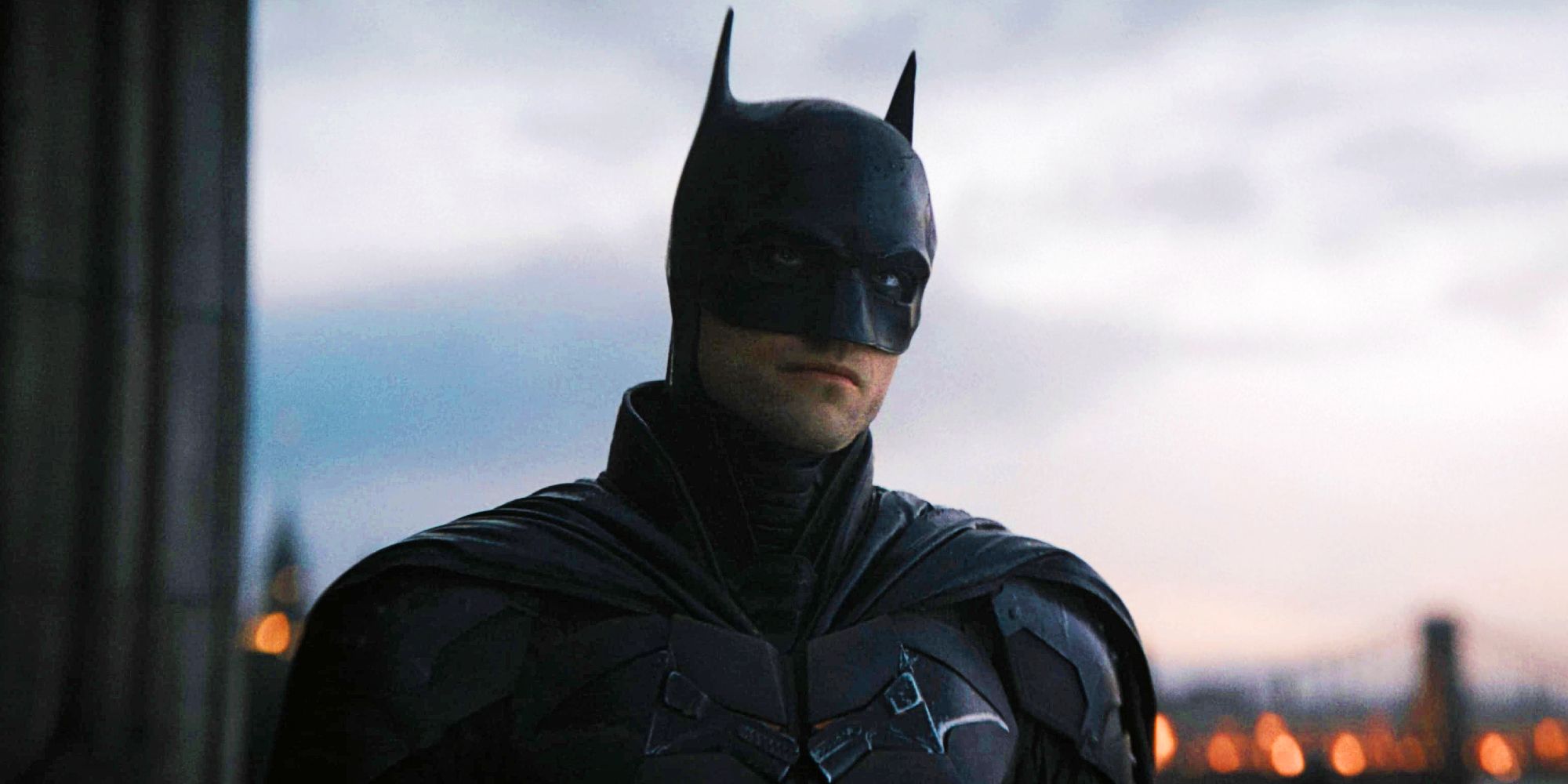 Robert Pattinson como Batman vestindo terno na frente da ponte em The Batman