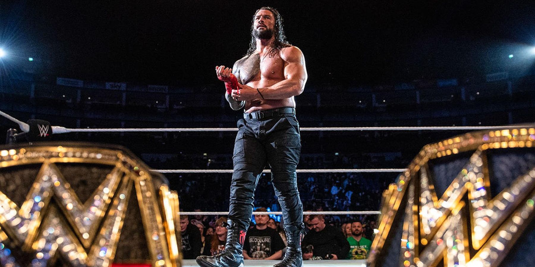 Roman Reigns prepares for a match in 2022 with the WWE Championship and Universal Championship in the foreground.