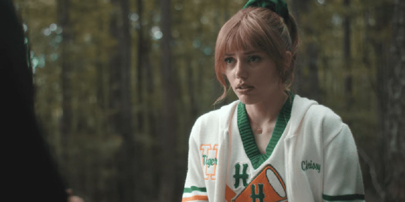 Chrissy in her cheerleader uniform sitting in the forest in Stranger Things