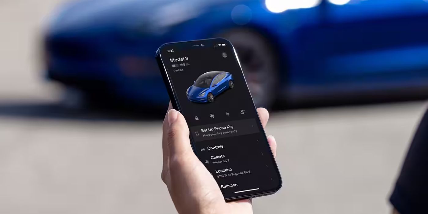 A hand holding a smartphone displaying the Tesla App