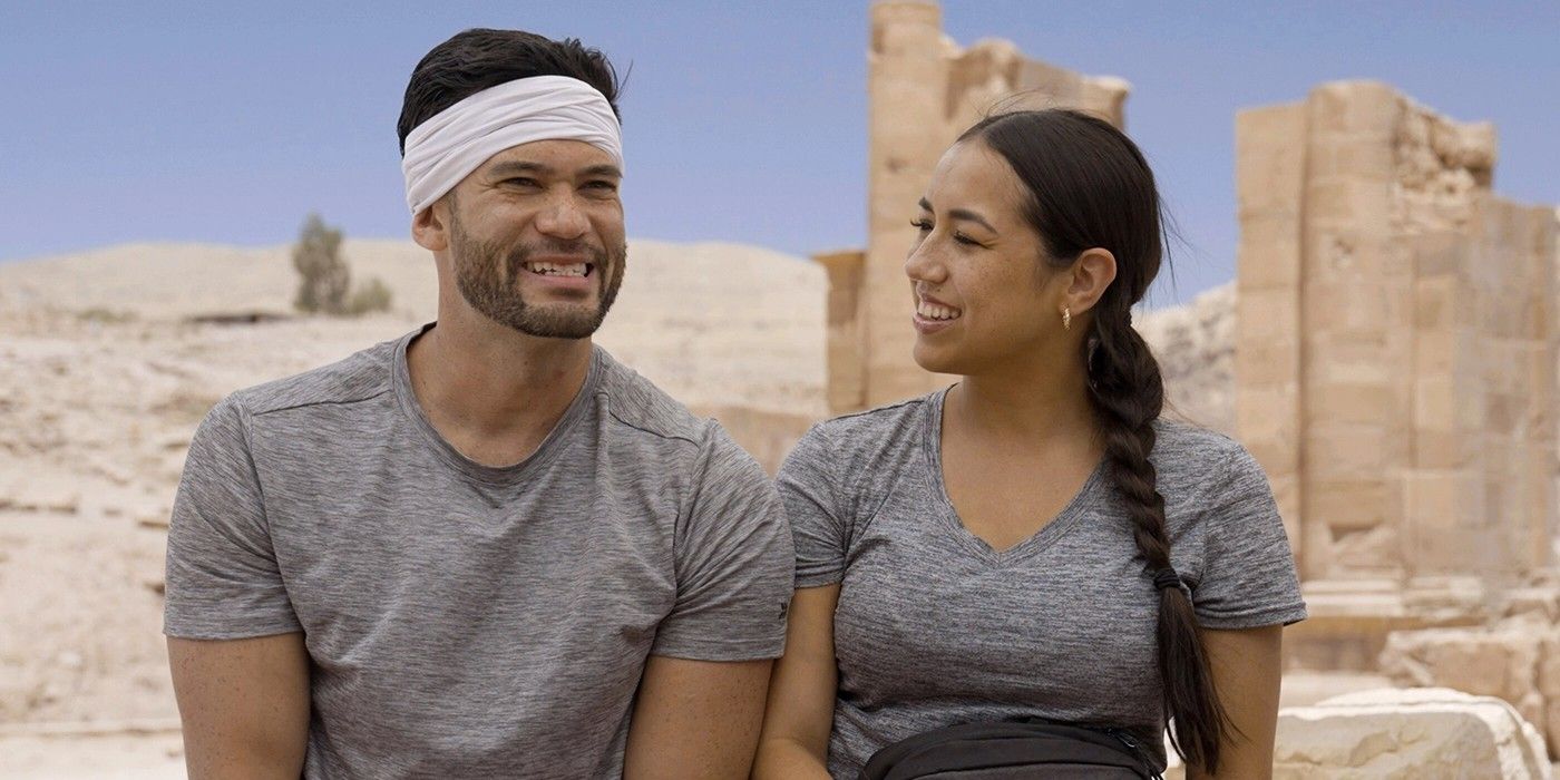 Luis and Michelle from The Amazing Race 34 smiling in grey t-shirts with Michelle looking over at Luis.