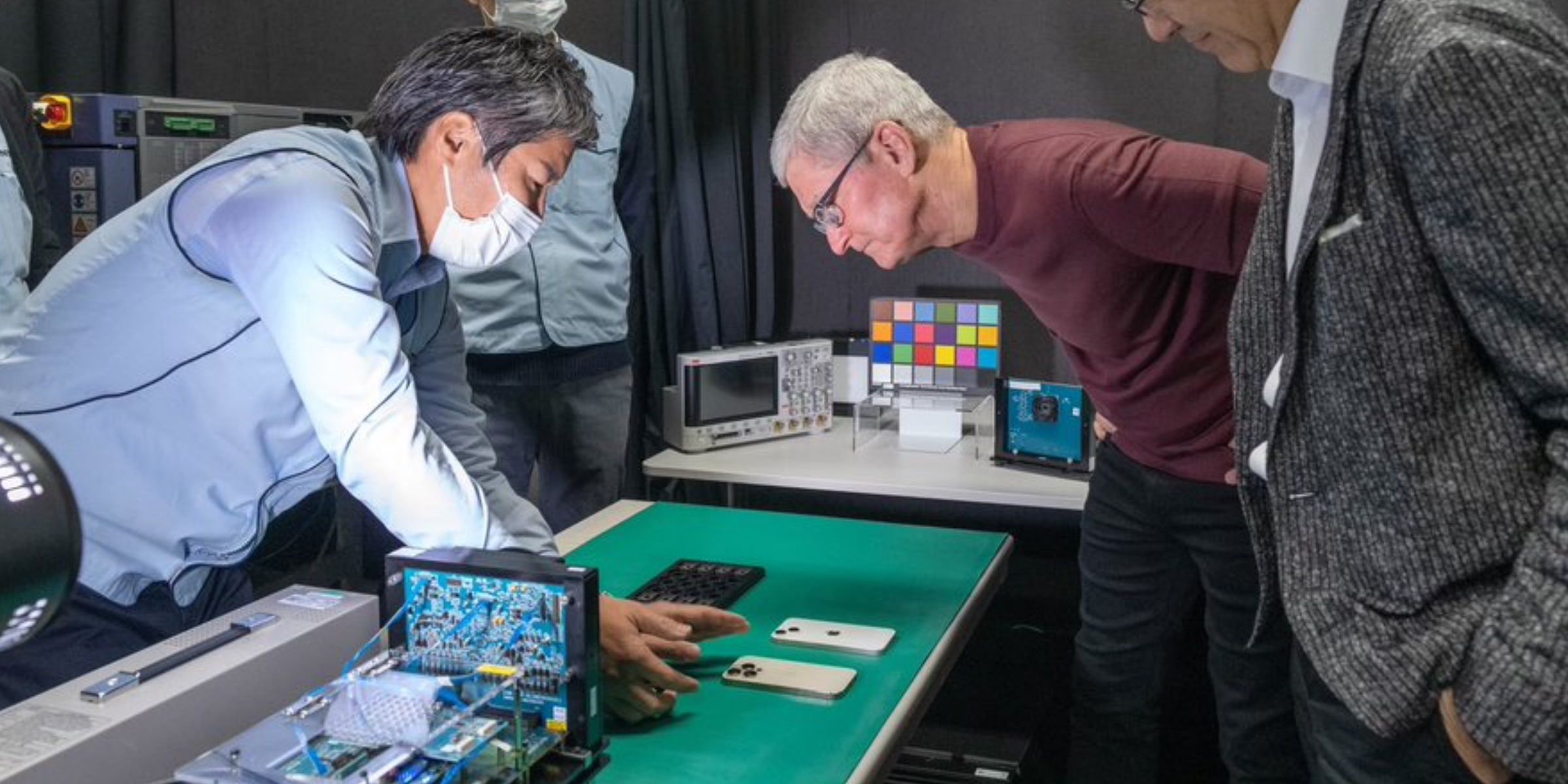 Apple CEO Tim Cook looking at an iPhone camera sensor at a Sony facility in Kumamoto, Japan.