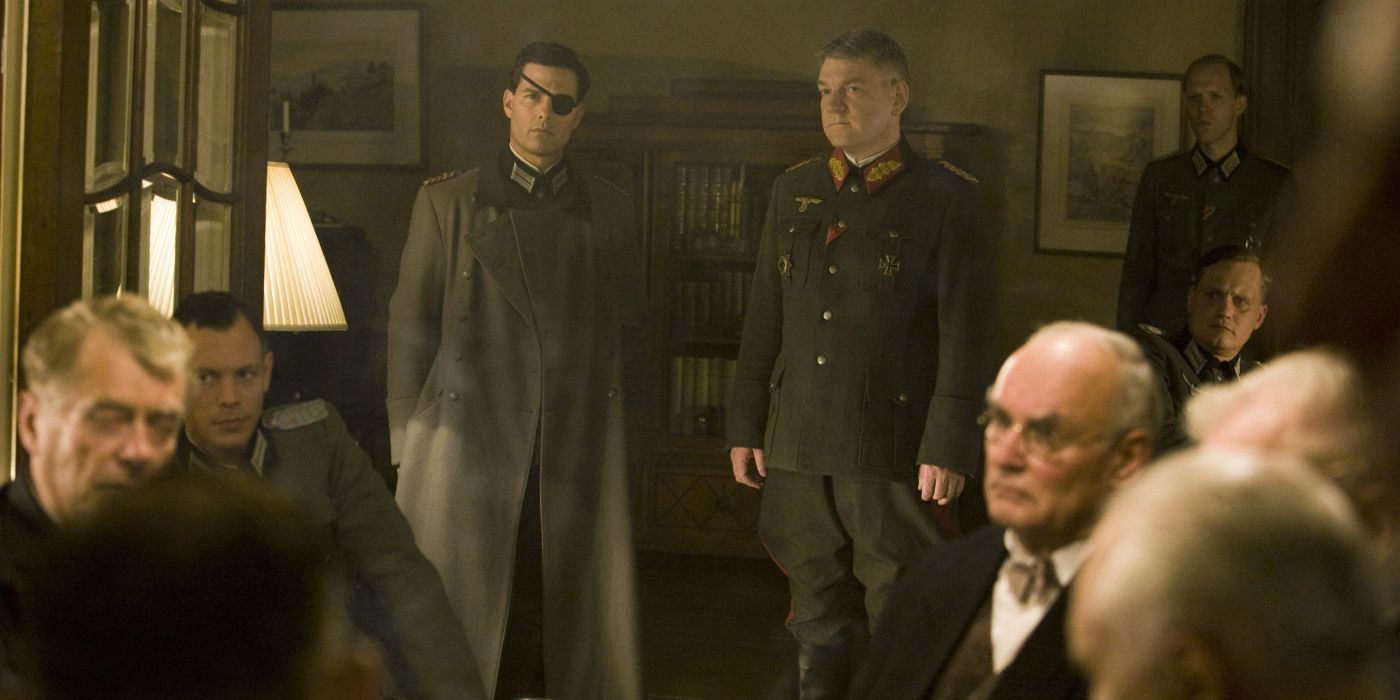Tom Cruise with an eye patch standing next to Kenneth Branagh in front of a group of seated men in valkyrie