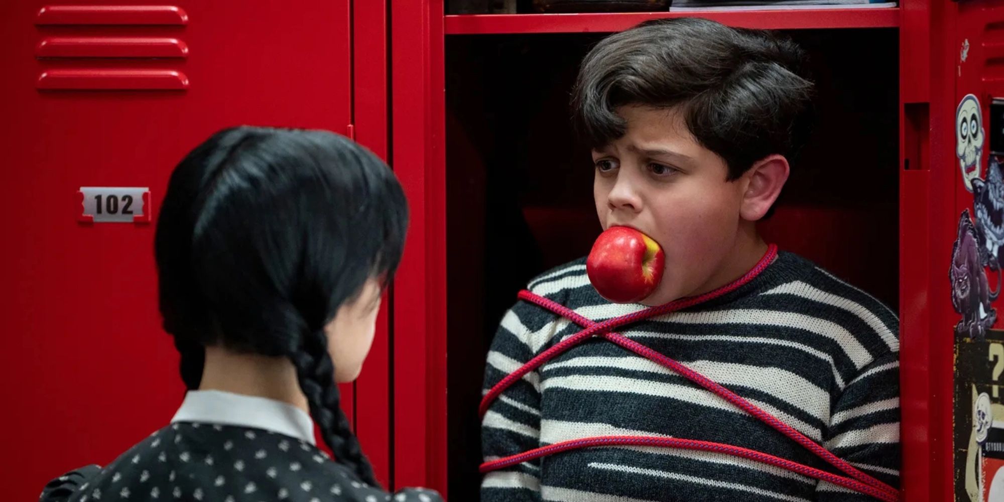 Pugsley Addams looks on while tied up in a locker with an apple in his mouth in Wednesday