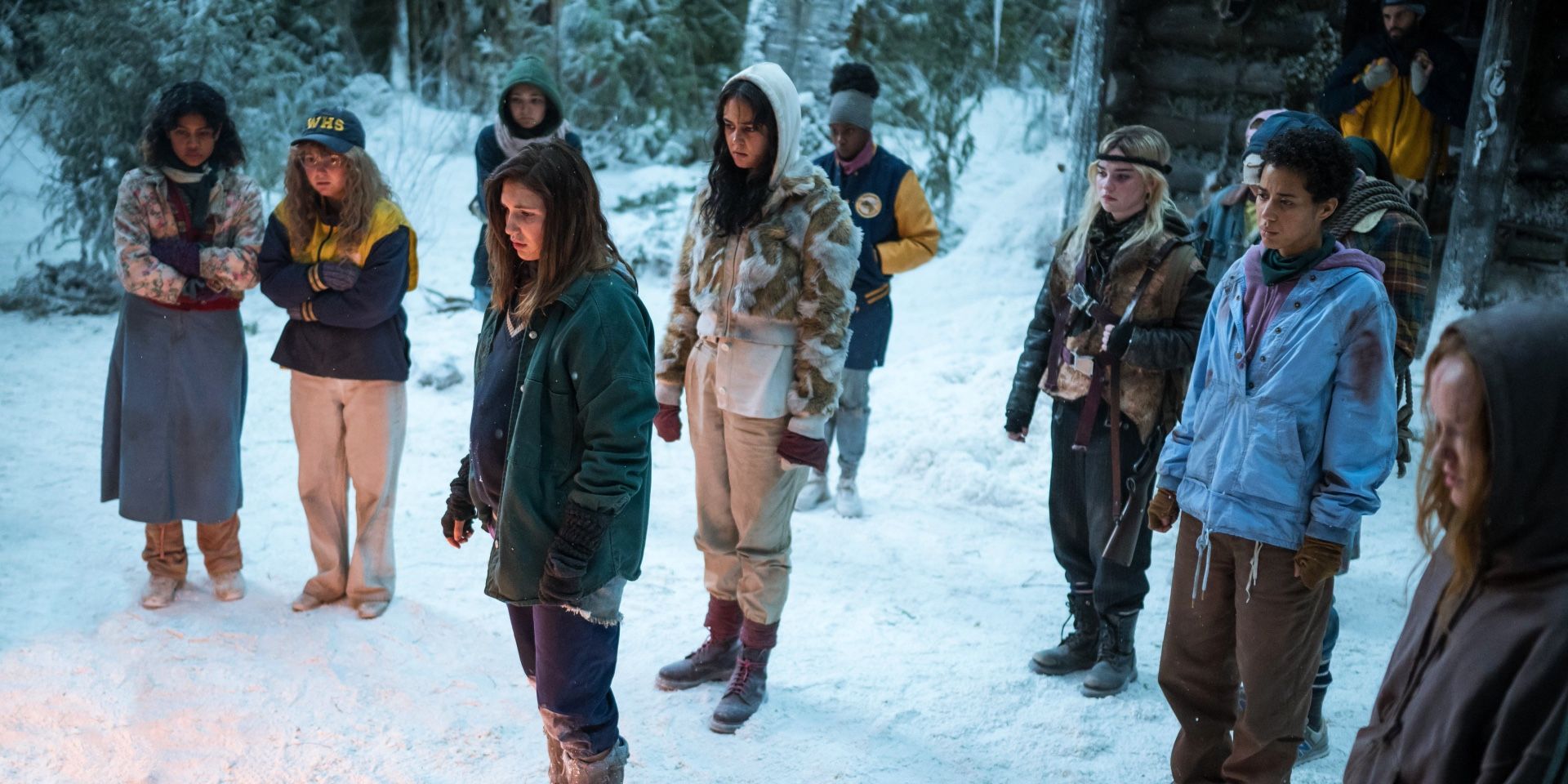 The soccer team stands outside the snowy cabin in Yellowjackets season 2