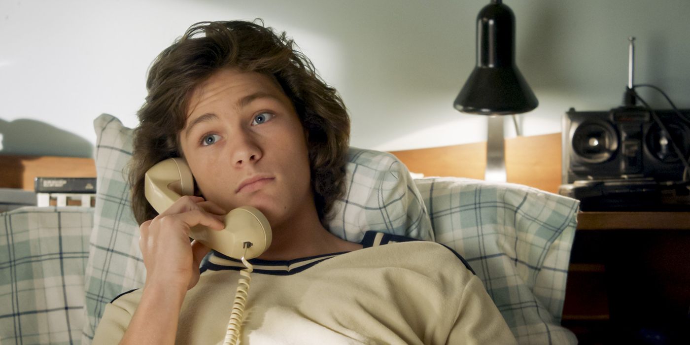 Georgie acostado en su cama hablando por teléfono en Young Sheldon.