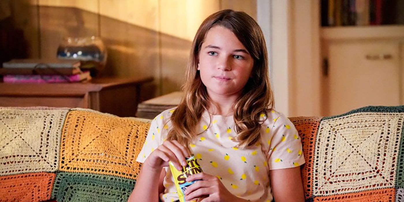 Missy from Young Sheldon sitting on the couch eating snacks.