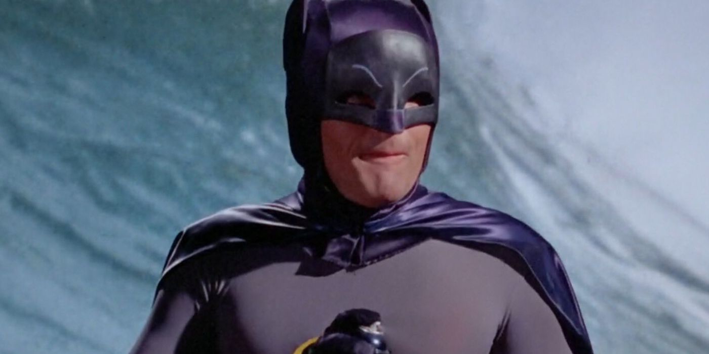 Batman holds a canister of shark repellent while surfing in the 1960s Adam West Batman TV series