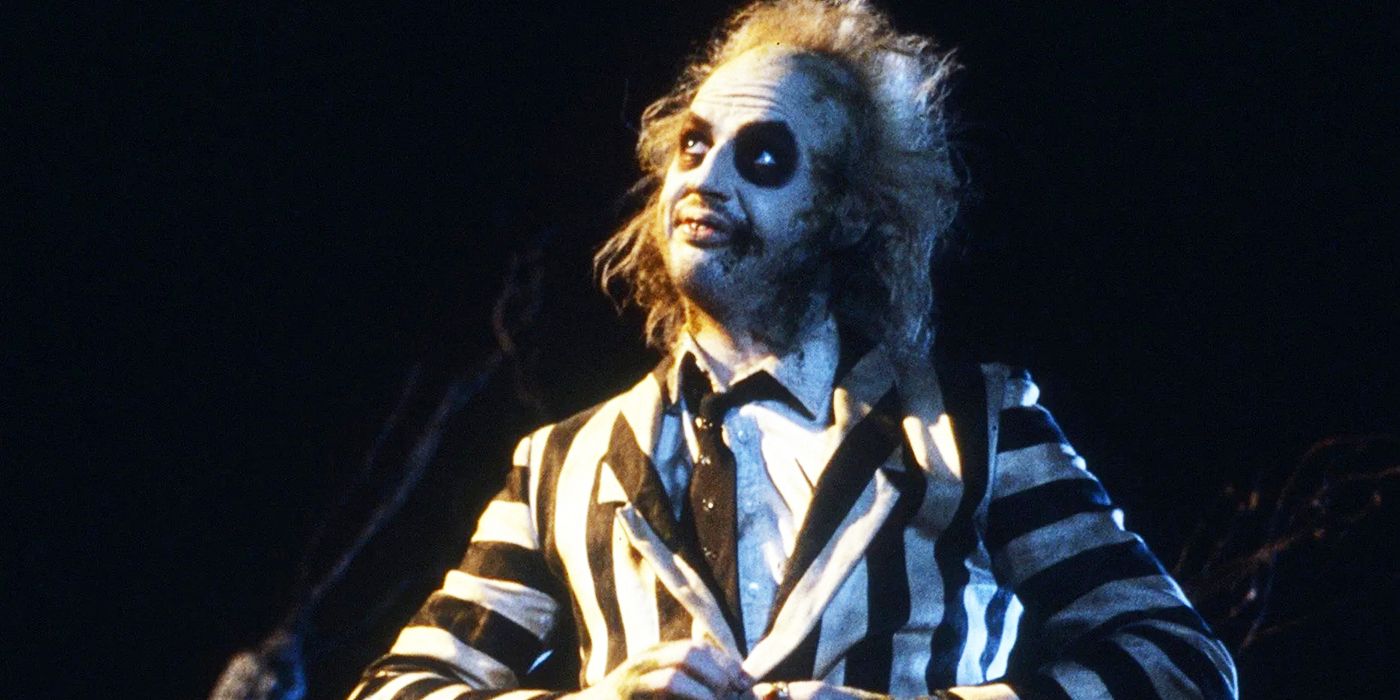 Michael Keaton como Beetlejuice sonríe mientras usa un esmoquin