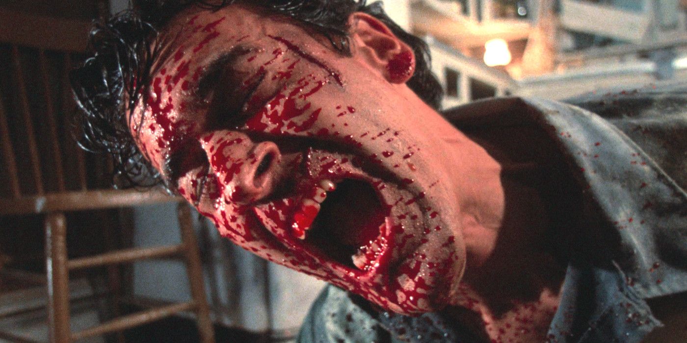 Bruce Campbell dans Evil Dead 2 tenant sa tête à un angle étrange tout en étant éclaboussé de sang au visage