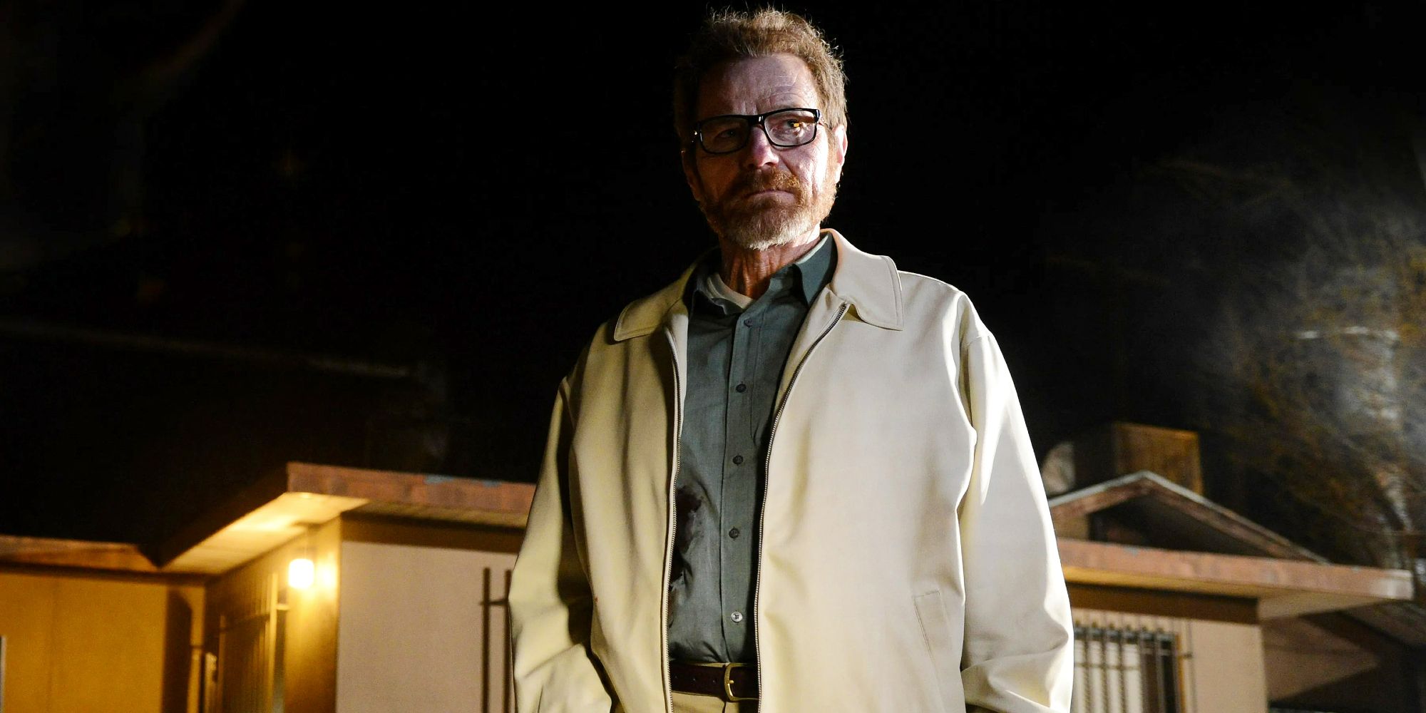 Bryan Cranston como Walter White vestindo jaqueta na frente de casa