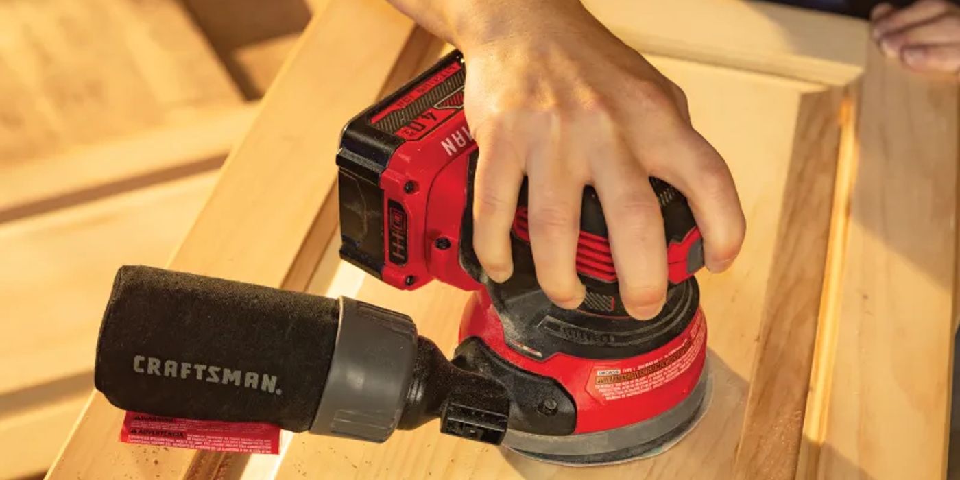 A hand uses a Craftsman orbital sander