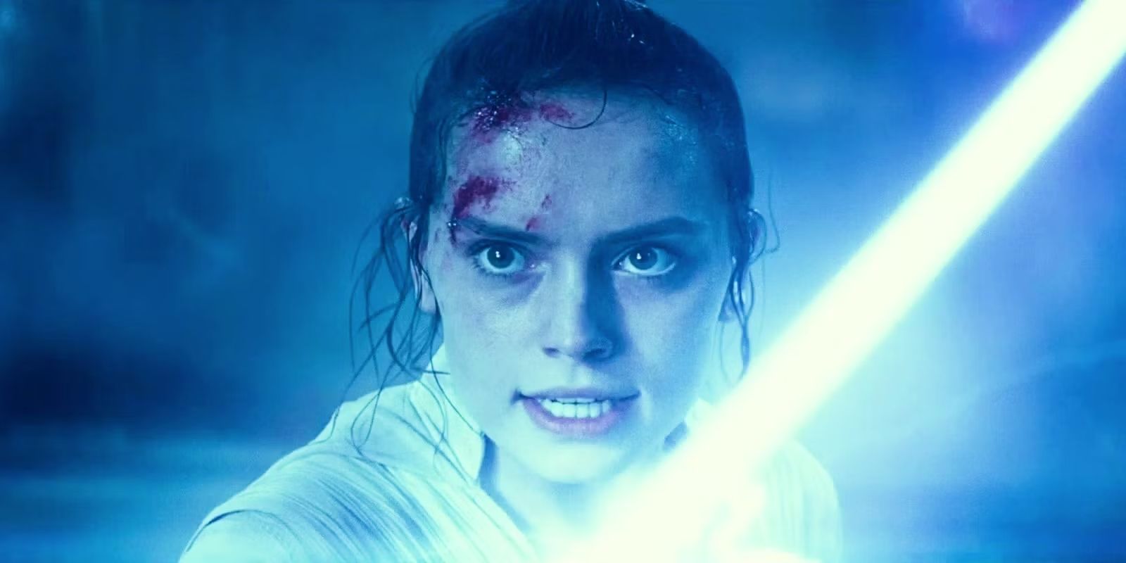 Rey in Star Wars: The Rise of Skywalker looking prepared to fight and holding up her blue lightsaber