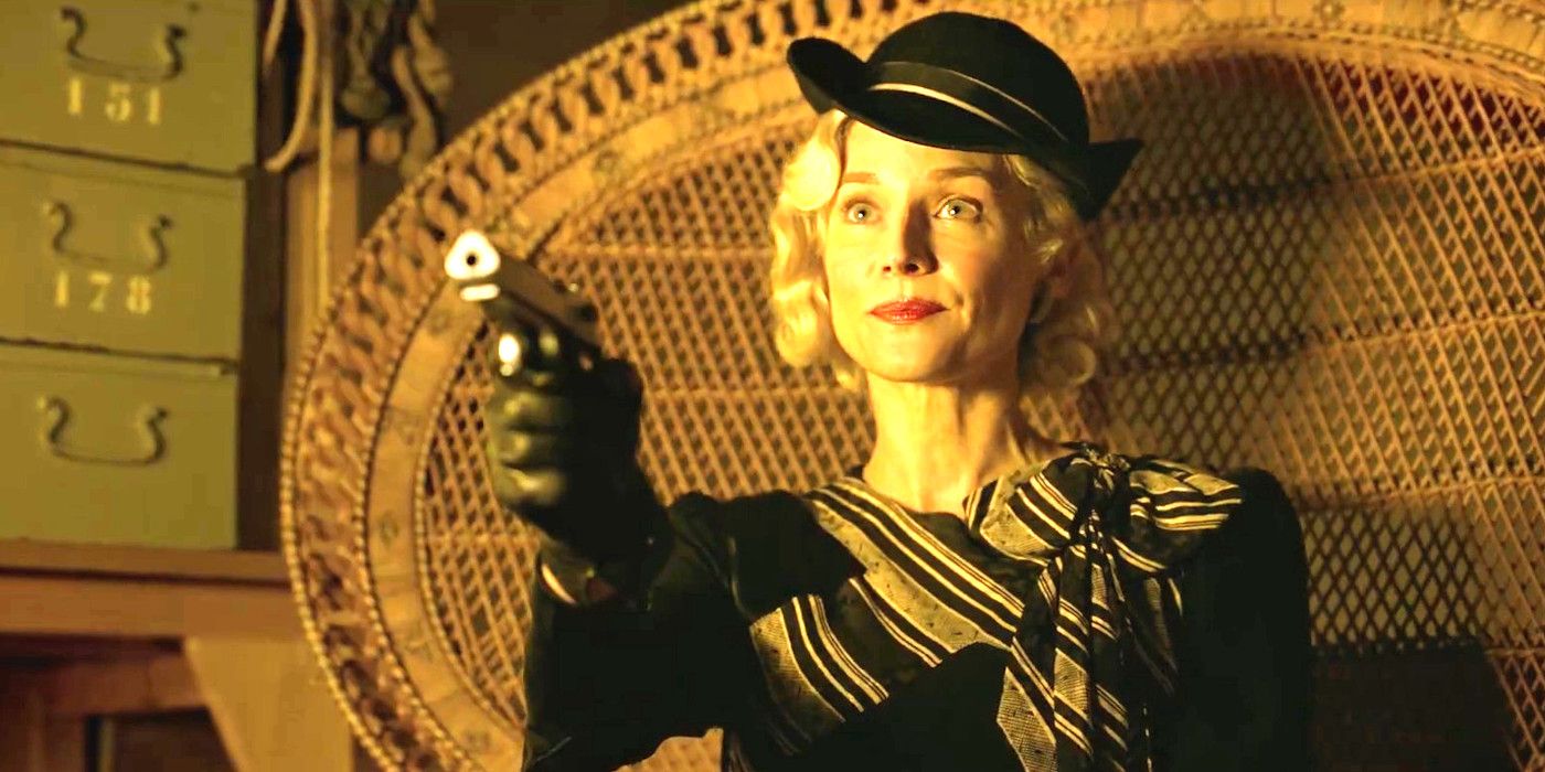 Diane Kruger In the movie Marlowe sitting in a chair in a hat with her lips pinched pointing a pistol