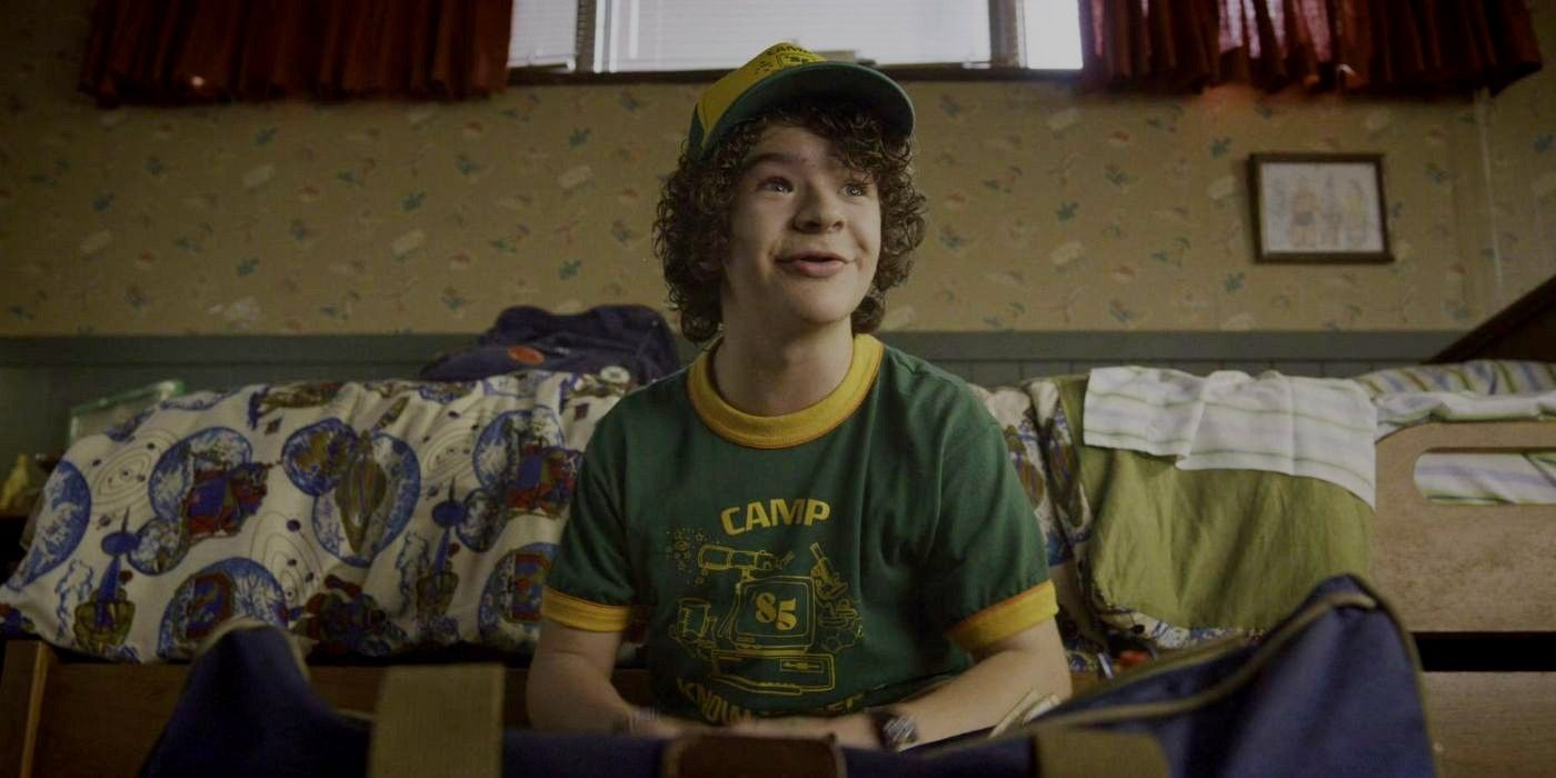 Dustin smiling while sitting on the counch in Stranger things