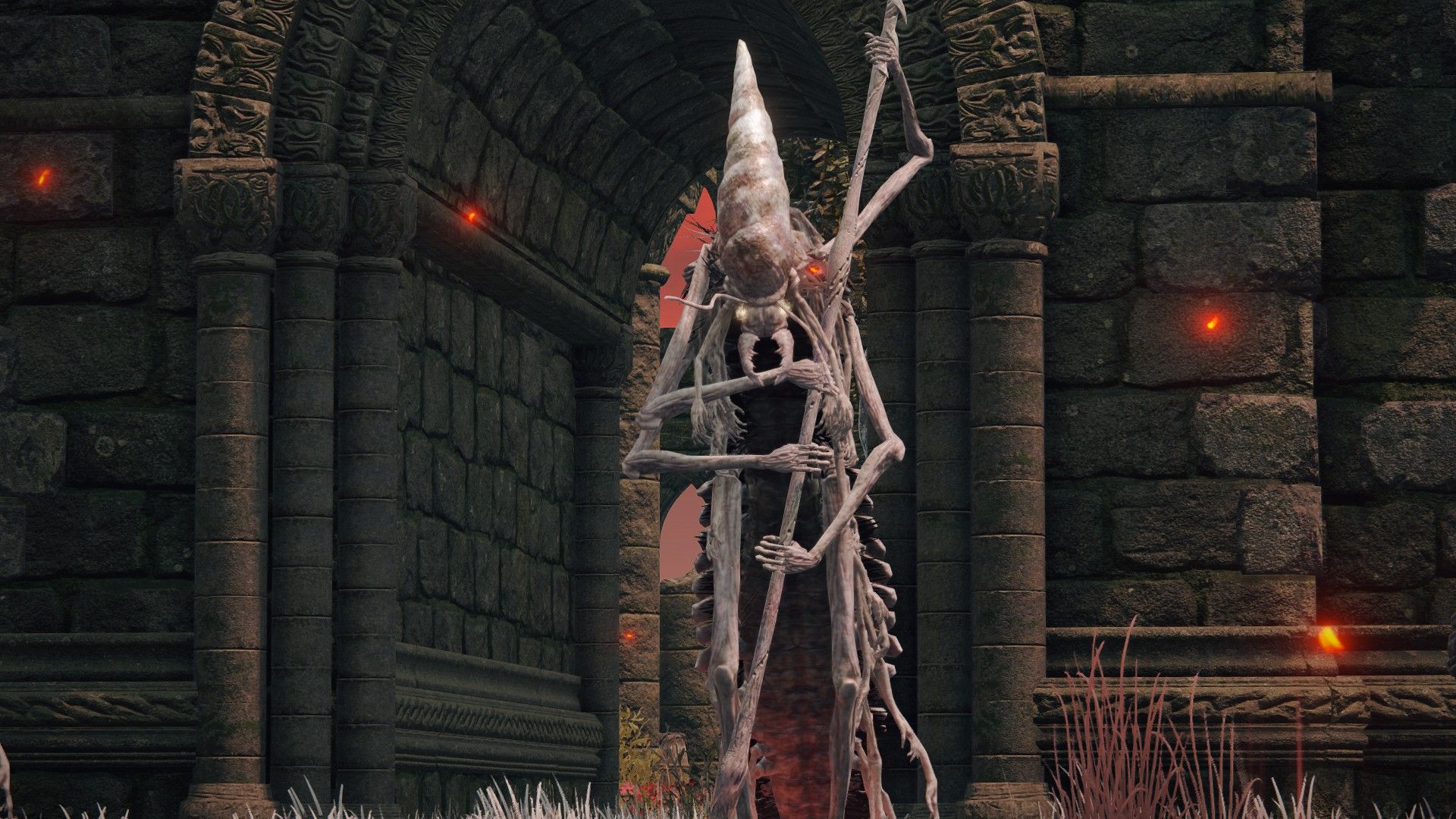 Elden Ring Pest, uma criatura humanóide centopéia, de pé e segurando uma arma alta na frente de uma estrutura de pedra.