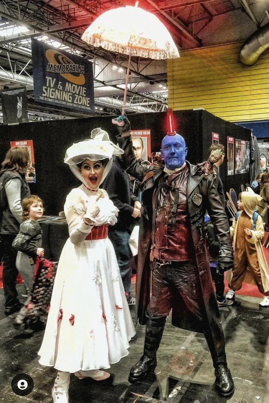 A cosplay of Mary Poppins with Yondu holding the umbrella 