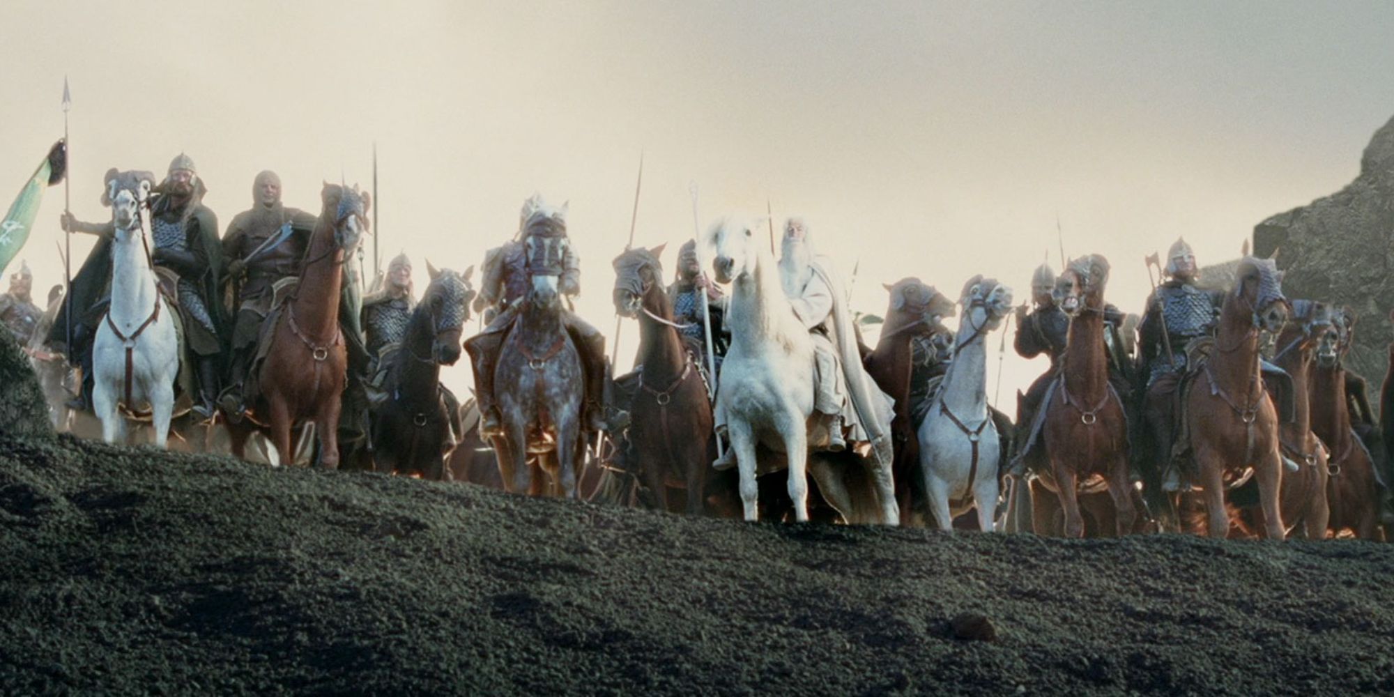 Gandalf on a horse in front of an army of knights looking down a hill at the end of LOTR: The Two Towers