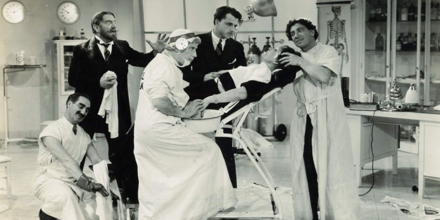 groucho chico and zippo marx pretending to be doctors and practicing on a woman in a chair with two men shocked in the background in a day at the races