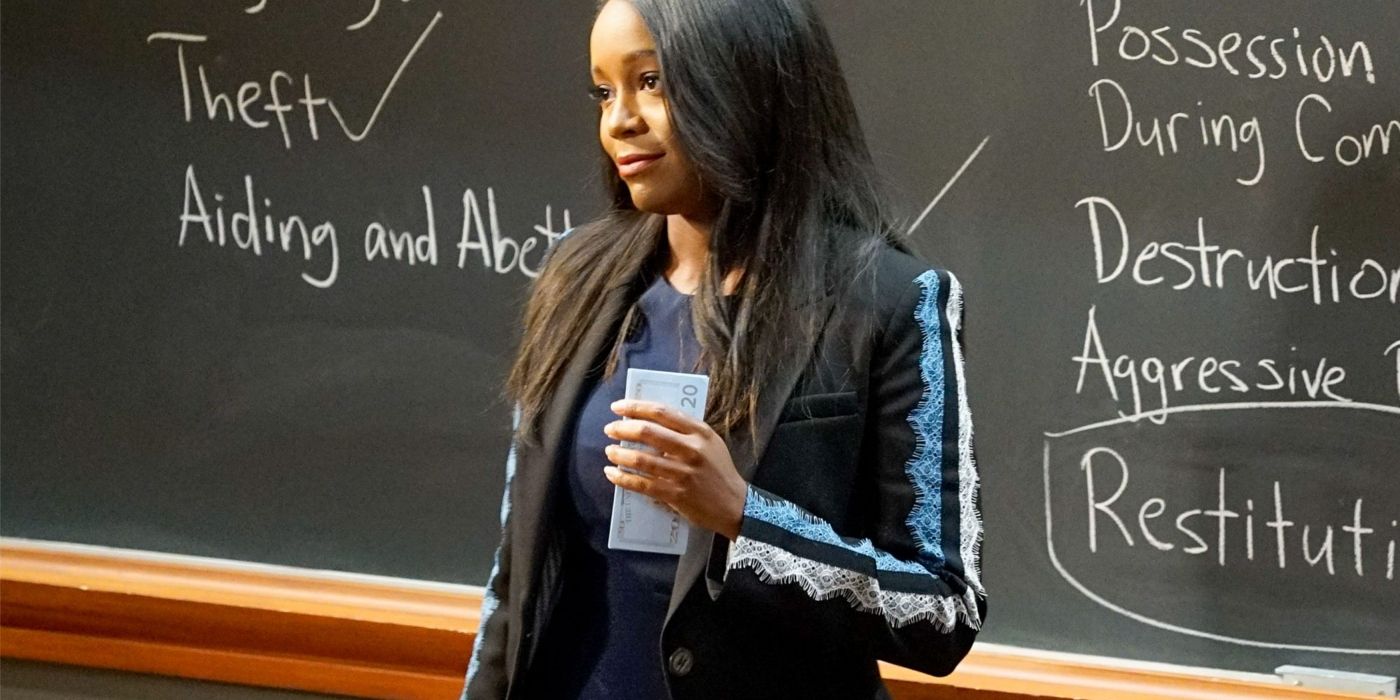 Michaela holding money in front of a chalkboard on HTGAWM