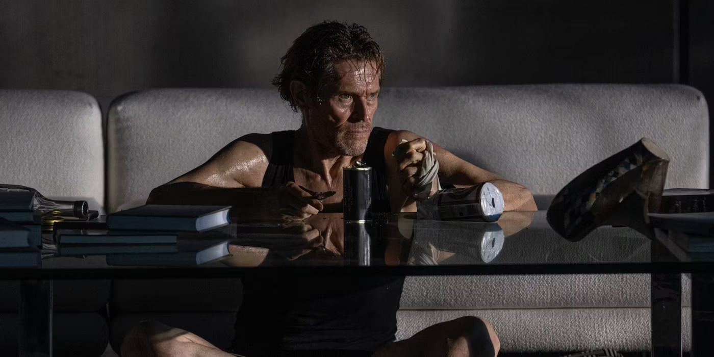 Willem Dafoe sentado em uma mesa em Inside