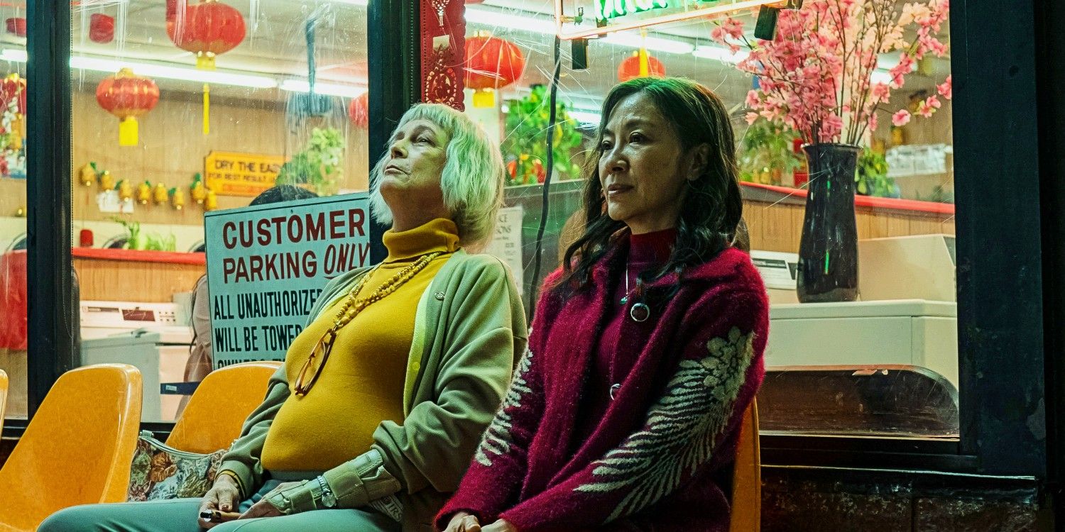 Deirdre Beaubeirdre (Jamie Lee Curtis) and Evelyn (Michelle Yeoh) sitting outside on the laundromat in Everything Everywhere All at Once.