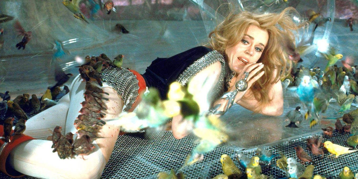 Jane Fonda lying on the ground with what look like leaves flying around her as Barbarella