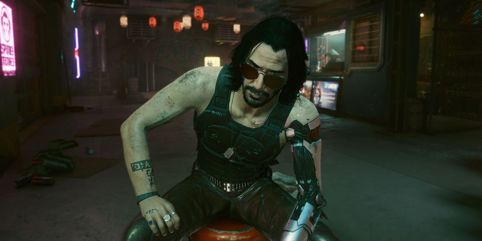 Johnny Silverhand sitting on a stool looking at the player over his sunglasses in Cyberpunk 2077
